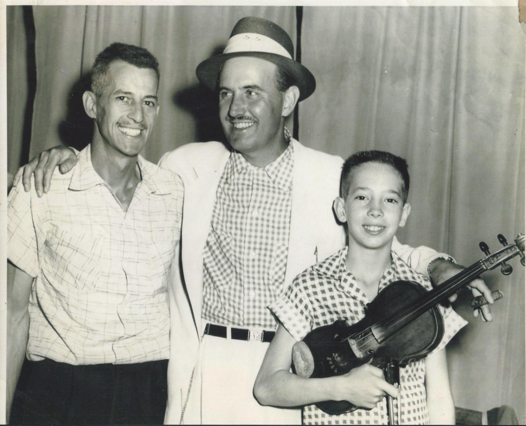 Joe Burchfield of the Burchfield Brothers poses with East Tennessee musical icon Archie Campbell and his young son Tommy Burchfield, who is holding a violin.